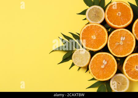 Composition de moitiés de citrons et d'oranges avec feuilles vertes sur fond jaune vif, vue de dessus, espace de copie Banque D'Images