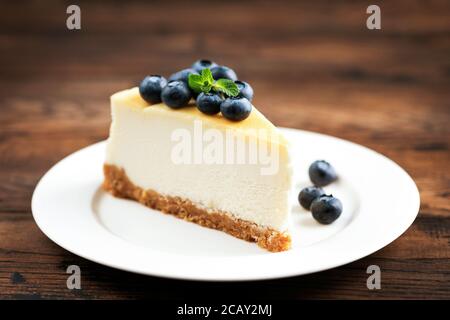 Tranche de cheesecake avec bleuets isolés sur fond de table en bois Banque D'Images