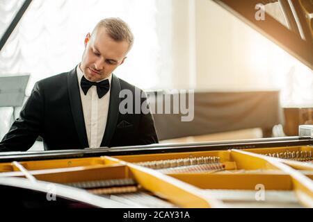 talentueux jeune pianiste caucasien, homme pratiquant, interprétant une musique impressionnante. musicien en costume élégant et formel jouer au piano Banque D'Images