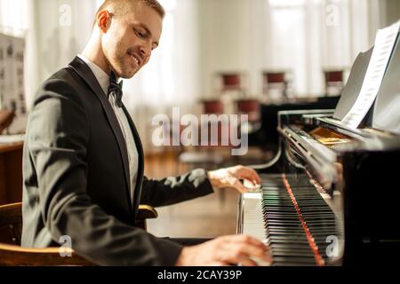 un musicien professionnel de race blanche joue avec élégance du piano sur une scène, un pianiste talentueux dans un costume élégant et formel, qui joue de la musique Banque D'Images