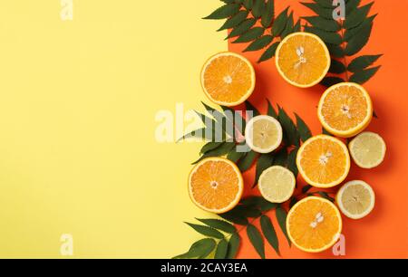 Composition des moitiés de citrons et d'oranges avec feuilles vertes sur un arrière-plan jaune-orange lumineux avec un espace pour le texte Banque D'Images