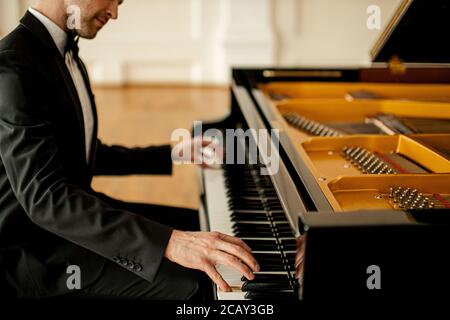 pianiste caucasien professionnel pratiquant avant un concert sur une scène. un homme charmant joue de la musique classique Banque D'Images