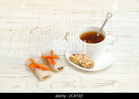 Tasse de thé et quelques barres de muesli. Fond en bois blanc Banque D'Images