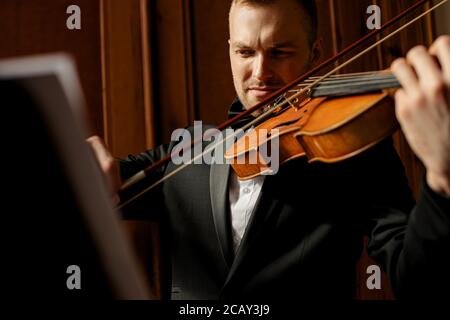 un jeune homme professionnel talentueux joue avec élégance du violon, un musicien séduisant en costume élégant et formel, joue de la musique classique Banque D'Images