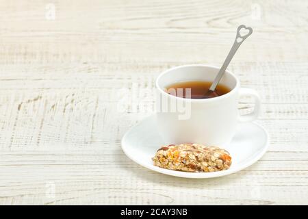 Tasse de thé et un bar de muesli. Fond en bois blanc Banque D'Images