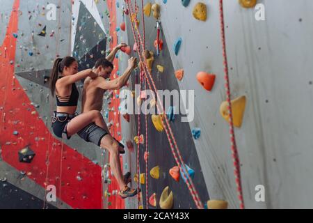 Sportif, homme et femme, participant à une compétition d'escalade. Photo sur toute la longueur avec vue latérale. Espace pour copier. Les étudiants ont le plaisir de monter Banque D'Images