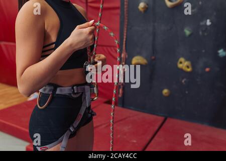 une petite fille à coupe près du corps avec une ceinture et une corde est prête pour l'escalade. gros plan vue latérale photo rognée. espace de copie Banque D'Images