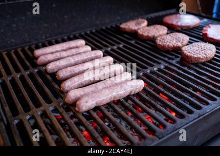 Saucisses et hamburgers cuisson sur le gril.cuisson de la viande sur un barbecue, mise au point sélective.côtelettes de viande de hamburger rôtisant sur le gril à l'extérieur. Banque D'Images