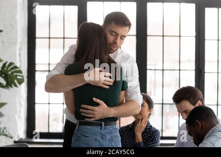 L'homme et la femme bouleversés se embrassant lors de la séance de thérapie de groupe Banque D'Images