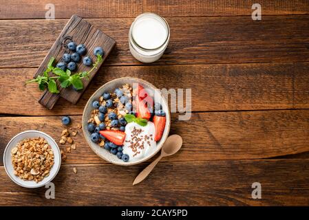 Dans un bol, faire l'avoine avec du yogourt grec et des baies d'été. Vue de dessus sur une table rustique en bois, espace de copie. Nutrition, alimentation saine concep Banque D'Images