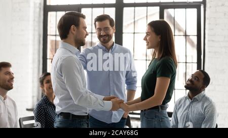 Un jeune couple heureux et réconcilié tient la main lors d'une séance de conseil en groupe Banque D'Images