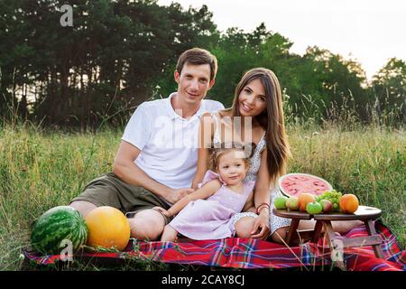 belle famille, maman, papa et fille assis sur un pique-nique avec la pastèque Banque D'Images