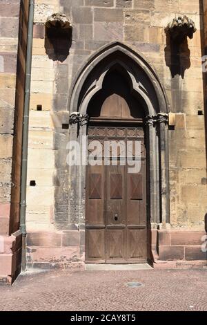 Ancienne porte en bois lourde de style architectural gothique pour entrer dans l'église Saint-Martin de la ville française de Colmar. Banque D'Images