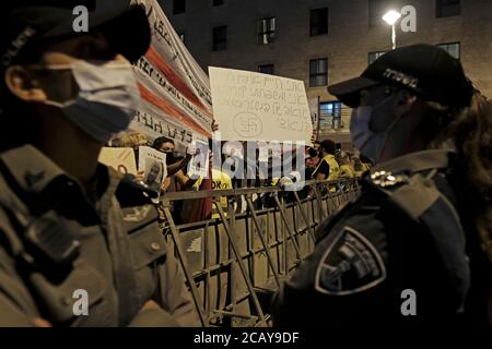 Un manifestant vêtu d'un uniforme de prison tient un écriteau avec un dessin d'une croix gammée et un texte qui dit « moi et ma famille sont victimes d'un régime nazi » alors que les manifestants affrontent la police lors d'une manifestation à laquelle assistaient plus de 15,000 personnes rassemblées devant le responsable du Premier ministre Résidence le 08 août 2020 à Jérusalem, Israël. Les Israéliens sont descendus dans la rue dans des manifestations presque quotidiennes pour appeler à la démission de Netanyahou suite à ses accusations de corruption, accusé de mauvaise gestion de la crise du coronavirus et son agression contre la démocratie. Banque D'Images