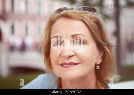 Portrait de la charmante et joyeuse femme blanche de race blanche d'environ 60 ans dans le centre-ville. Femme âgée attrayante pose à l'extérieur. Banque D'Images