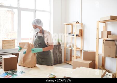 Portrait de la femme qui porte des vêtements de protection lors de l'emballage des commandes au service de livraison de nourriture, espace de copie Banque D'Images