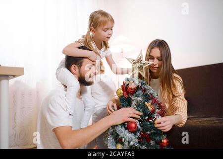 la famille de caucasiens heureux se composait de parents, d'enfants et de chiens de compagnie se préparant pour la nouvelle année, décorant petit arbre de noël artificiel ensemble à la maison Banque D'Images