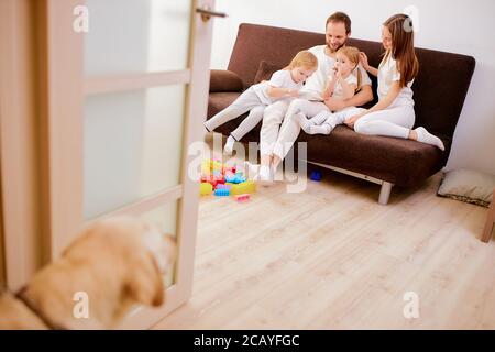 la famille sympathique et heureuse était composée de mère père et les enfants aiment passer du temps ensemble à la maison, s'asseoir sur un canapé et porter des vêtements blancs décontractés Banque D'Images