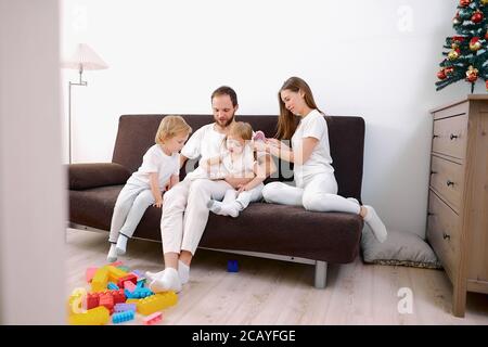 la famille sympathique et heureuse était composée de mère père et les enfants aiment passer du temps ensemble à la maison, s'asseoir sur un canapé et porter des vêtements blancs décontractés Banque D'Images