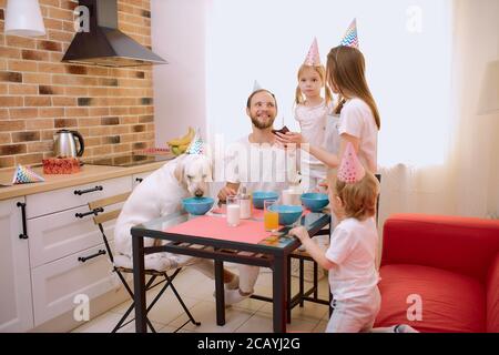 la famille caucasienne se composait de mère, de père, d'enfants adorables et d'un chien blanc sympathique qui célébrait les jours d'anniversaire ensemble à la maison, en cuisine Banque D'Images