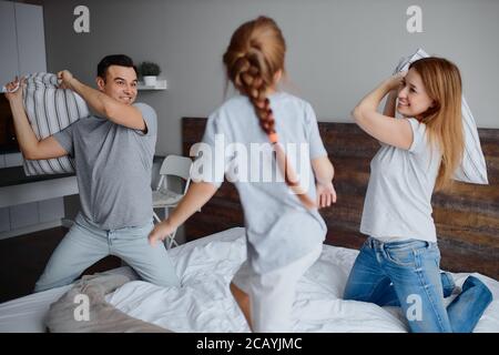 la famille caucasienne se composait de mère père et de fille d'enfant s'amusant ensemble jouant avec des oreillers à la maison sur le lit Banque D'Images