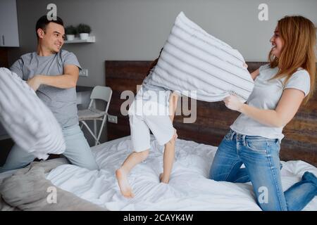 la famille caucasienne se composait de mère père et de fille d'enfant s'amusant ensemble jouant avec des oreillers à la maison sur le lit Banque D'Images