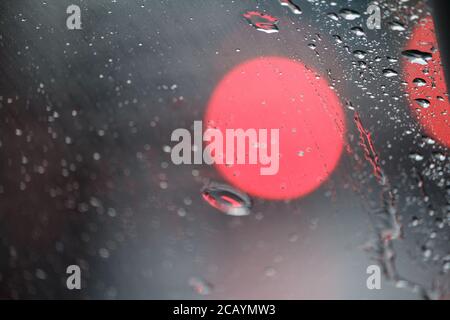 Gros plan de verre avec gouttes de pluie et réflexions de lumière, gouttes d'eau sur le verre de voiture, mise au point sélective Banque D'Images