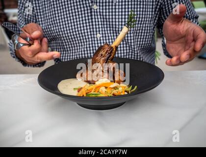 Détail de l'homme caucasien dans une chemise à carreaux allant manger de l'agneau rôti. Cuisine croate au restaurant. Banque D'Images