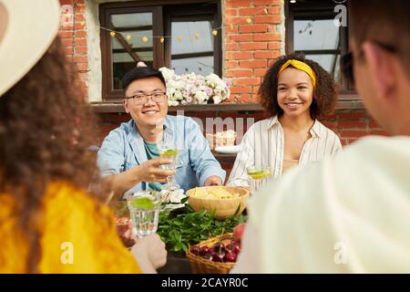 Groupe multiethnique d'amis qui dînent ensemble à l'extérieur tout en étant assis à table sur la terrasse ouverte, espace de copie Banque D'Images
