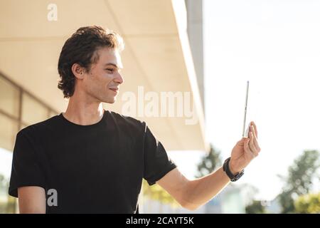 Jeune homme caucasien ayant une conférence téléphonique à l'aide d'une tablette numérique à l'extérieur bureau Banque D'Images