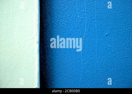 Deux tons de bandes de couleur bleue sur un mur fraîchement peint en lumière dure, décalé avec une grande partie plus sombre. Banque D'Images