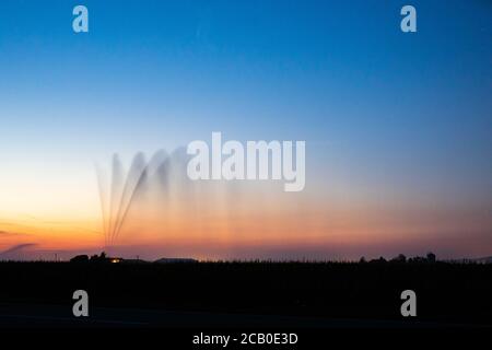 Hartheim am Rhein, Allemagne. 09e août 2020. Un système de gicleurs irrigue un champ après le coucher du soleil. En raison des températures élevées et de la sécheresse persistante, l'Allemagne connaît actuellement une période de sécheresse historique (la photo a été prise avec un long temps d'exposition) crédit: Philipp von Ditfurth/dpa/Alamy Live News Banque D'Images