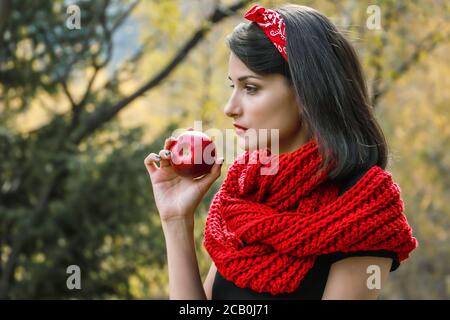 Une grande pomme mûre dans une main de femme sur un fond de foulard rouge Banque D'Images