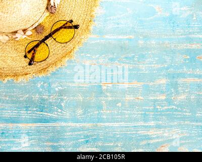 Accessoires de plage, chapeau de paille et lunettes de soleil sur une planche en bois bleu vintage avec espace de copie. Voyage et vacances vacances d'été arrière-plan, vue de dessus. Banque D'Images