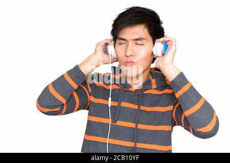 Studio de jeune homme asiatique élégant qui écoute de la musique avec casque isolé sur fond blanc Banque D'Images