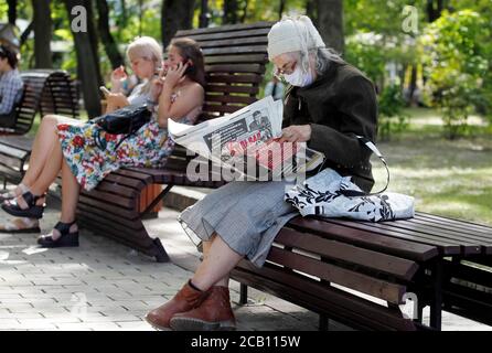 Kiev, Ukraine. 09e août 2020. Une femme âgée portant un masque facial comme mesure préventive est assise sur un banc lors de la lecture d'un journal dans un parc.le nombre de cas de coronavirus COVID-19 a augmenté rapidement, augmentant de près de 2.5 fois au cours de l'été en Ukraine. Crédit : SOPA Images Limited/Alamy Live News Banque D'Images