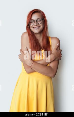 Photo en gros plan d'une gentille dame de gingembre caucasien qui embrasse elle porte une robe jaune sur le mur blanc du studio Banque D'Images