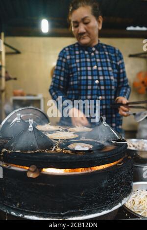 Ho Chi Minh ville, Vietnam - 02 août 2020: Femme vietnamienne cuisant Banh xeo - crêpes vietnamiennes ou crêpes vietnamiennes faites à partir de farine de riz et fourré W Banque D'Images