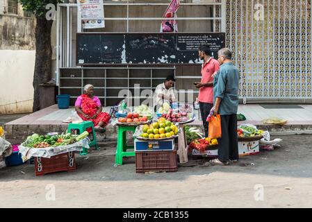 Mumbai, Inde - 22 novembre 2019 : une femme et un homme indiens vendent des fruits et des légumes sur un marché de rue à Mumbai (connu en Inde sous le nom de Bombay). Banque D'Images