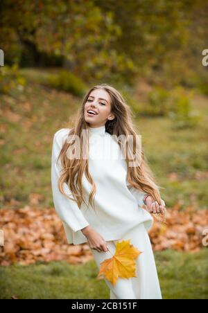 Vogue de l'automne. Jeune fille taille basse élégante portant une robe moderne dans un parc urbain souriant heureux. Modèle caucasien féminin. Mode d'automne. Banque D'Images