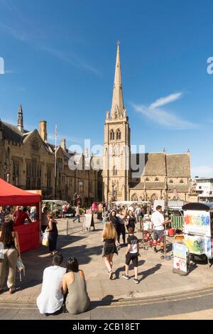 Jeune couple assis sur les marches de la place du marché de la ville de Durham avec l'église Saint-Nicolas en arrière-plan, Angleterre, Royaume-Uni Banque D'Images