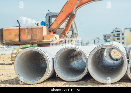 Cheminée de tuyaux de drainage en béton pour puits évacuation d'eau en posant un système d'égout externe sur un chantier de construction à l'extérieur d'un entrepôt. Infrastructure civile str Banque D'Images