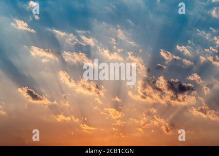 Les rayons du soleil se brisent à travers les nuages dans un ciel bleu spectaculaire avec couleurs de coucher de soleil Banque D'Images