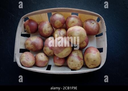 Pommes de terre des îles Canaries, variété rose dans un panier sur fond noir (pommes de terre roses Canaries) Banque D'Images