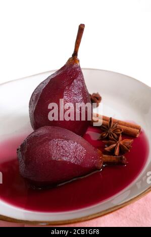 Poires pochées au vin rouge avec épices. Dessert sucré, recette de cuisine italienne. Banque D'Images
