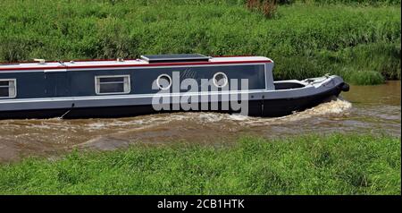 Un bateau étroit à canal gris et boron, « Meg no 2 », pousse contre la marée entrante alors qu'il se déplace le long de la rivière Douglas et provoque une vague d'arbals. Banque D'Images