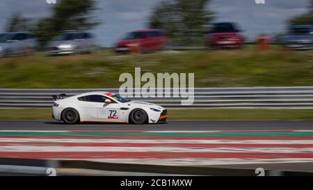 Une photo panoramique d'une voiture de course blanche en circuit sur une piste. Banque D'Images