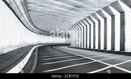 Filtre de lumière du soleil entre les colonnes dans un demi-tunnel vide le long d'un route côtière Banque D'Images