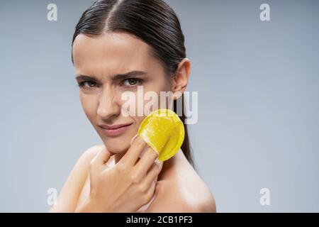 Jeune femme charmante utilisant une éponge exfoliante Banque D'Images