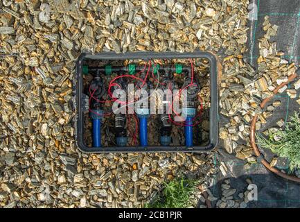 Gros plan des électrovannes hydrauliques automatisées dans le système de gicleurs d'irrigation souterrains Home Garden. Banque D'Images